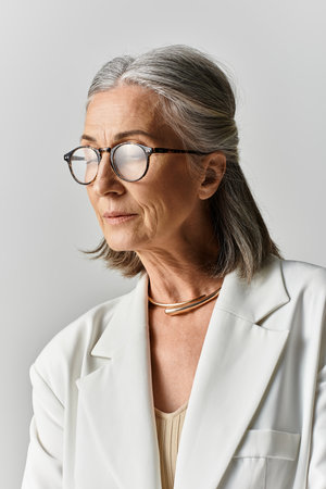 A sophisticated woman with grey hair exudes charm in a white suit, showcasing timeless elegance and style.の写真素材