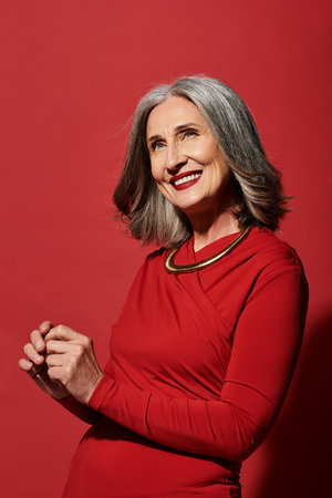 A beautiful mature woman with grey hair joyfully celebrates Christmas and welcomes the New Year in...