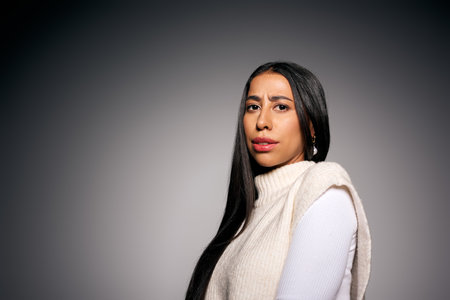 The beautiful young woman stands poised, showcasing her stylish outfit against a simple backdrop.の写真素材