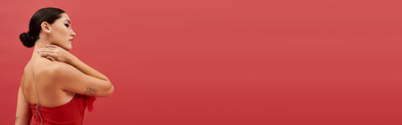 A young woman showcases her elegance while standing confidently against a bold red backdrop.の写真素材