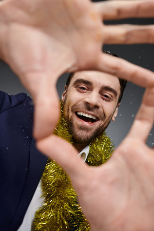 A young man with a big smile frames his face with hands decorated in festive attire.の写真素材