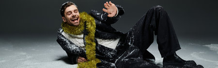 A young man with a cheerful smile enjoys playing in the snow while wearing a bright scarf.の写真素材