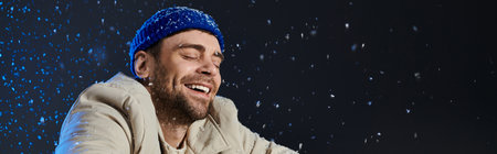 A smiling young man embraces the winter joy with snowflakes swirling around him indoors.の写真素材