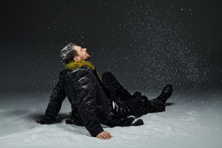A young man relaxes in the snow, watching snowflakes gently fall around him.の写真素材
