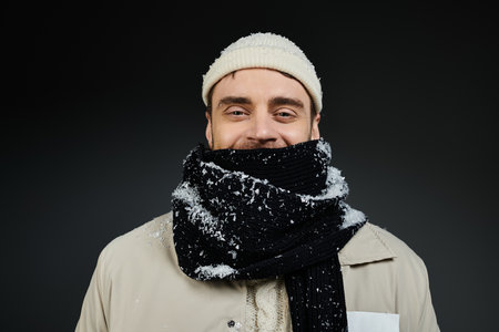This happy young man, wearing a thick scarf and warm gear, embraces winter vibes with joy.の写真素材