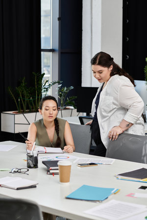 Two elegant business professionals discuss strategies while reviewing documents at a desk.の写真素材