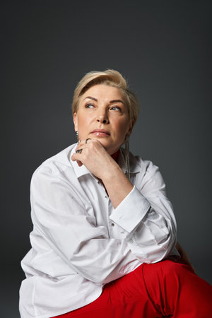 An elegant woman in stylish attire reflects on ideas with a contemplative expression.の写真素材