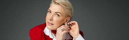 A chic woman in elegant attire adjusts her earrings, exuding sophistication and confidence.