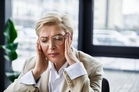 A fashionable adult woman shows signs of frustration while at her desk in an office setting.の写真素材