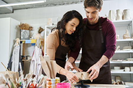 A couple joyfully shapes clay while crafting pottery in their creative space.