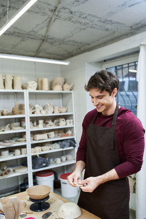 Hard working cheerful man with apron making pottery.の写真素材