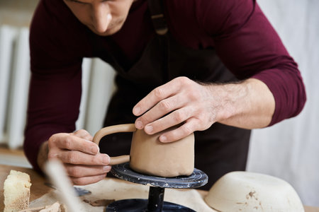 Young man in black apron making pottery with his hands.の写真素材