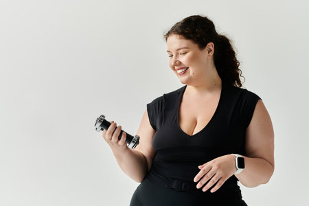 A beautiful plus size woman smiles while holding a weight, embodying confidence and strength.