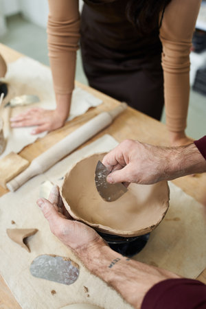 A couple shares love and creativity while shaping clay in a sunny workshop.