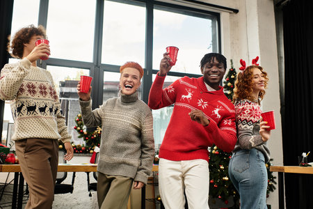 Colleagues share laughs and raise cups in celebration of Christmas at their workplace.の写真素材