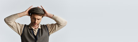 A dapper young man reflects while adjusting his fashionable hat, exuding charm and elegance.