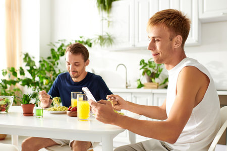 Two men happily eating together in their modern kitchen.の写真素材