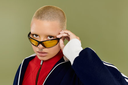 A vibrant young woman with a shaved head showcases her unique style while striking a pose.