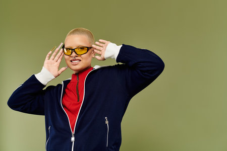 This vibrant young bald woman playfully poses in colorful attire with a confident smile.