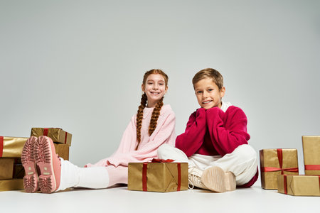 A girl and boy share smiles on the floor, enjoying the cozy winter vibe with gifts.の写真素材
