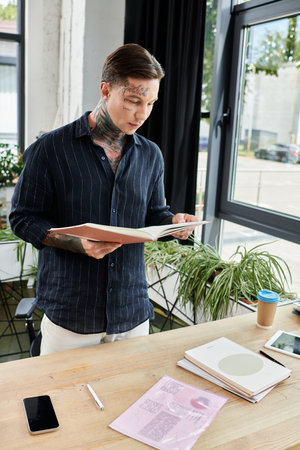 A young coworker reviews documents at a stylish office desk filled with stationery and greenery.の写真素材