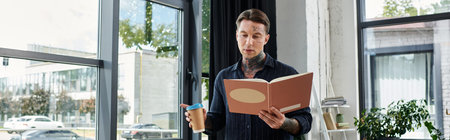 A young professional reviews notes while holding a coffee cup in a vibrant office environment.