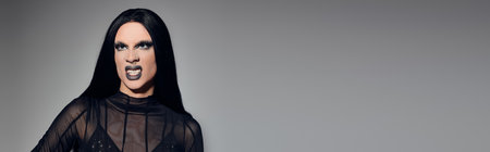 The stylish drag queen exudes confidence, showcasing a bold black ensemble in a modern studio...