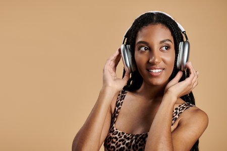 A young woman showcases her trendy outfit while happily listening to music with headphones.