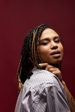 A young and stylish African American woman showcases her braided hairstyle in a chic studio...