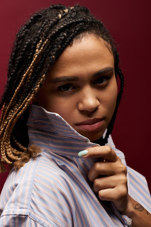A young African American woman with vibrant braided hair showcases her style against a striking...