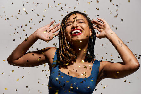 A young, fashionable woman with braided hair and red lips celebrates joyfully in a studio filled with confetti.の写真素材