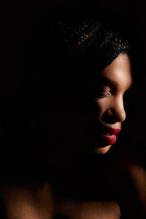 A young African American woman captivates the studio with her bold red lips.の写真素材