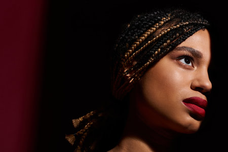 A young, fashionable woman with braided hair showcases her confident style while striking a pose in the studio.の写真素材
