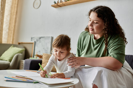 A loving mom encourages her daughter as they engage in a fun art activity together.の写真素材
