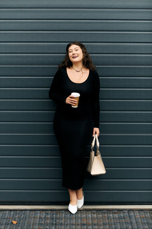 A young plus size woman delights in a crisp autumn day while casually strolling outdoors with her...