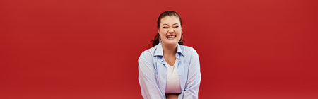 A cheerful plus size woman poses confidently in bright makeup, radiating beauty in a bold studio...