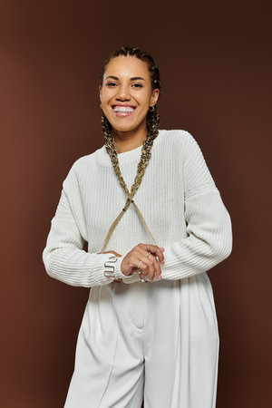 A cheerful young woman in cozy autumn attire beams with joy, radiating warmth and style.