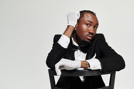 A young man in a tailored suit showcases confidence and elegance while posing on a grey background.の写真素材