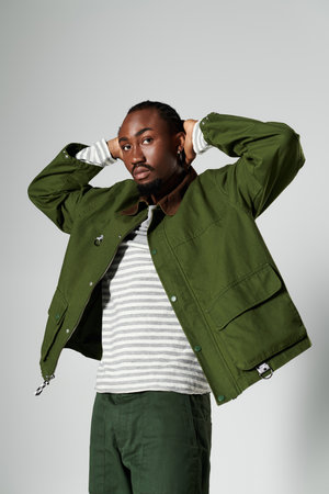 A young African American man strikes a pose in fashionable green attire, exuding confidence and...