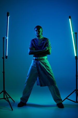 A young man exudes confidence in stylish attire, illuminated by vibrant neon lights in a studio.