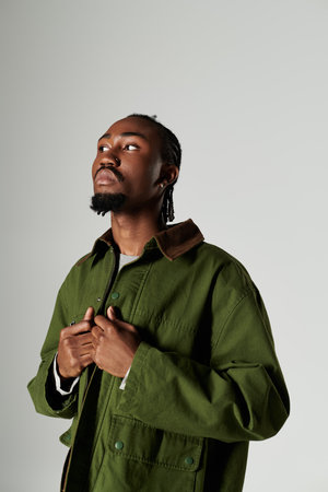 A young African American man showcases his fashion in a striking green outfit on a neutral backdrop.の写真素材