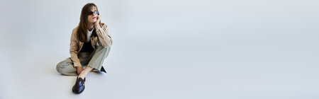 The young man showcases his trendy outfit while sitting relaxed in a serene environment.の写真素材