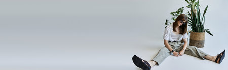 A fashionable young man enjoys a moment of tranquility surrounded by greenery in a bright room.の写真素材