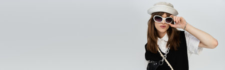 A stylish young man confidently poses in trendy clothes against a neutral background.の写真素材