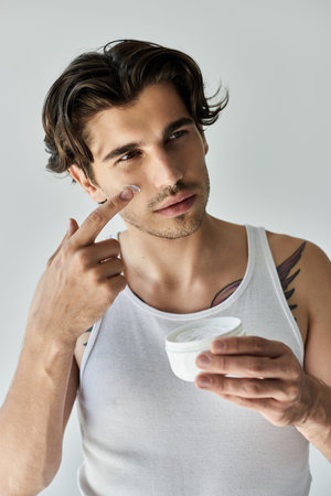 This young man confidently applies skincare, blending modern style with a touch of personal art in a chill atmosphere.の写真素材