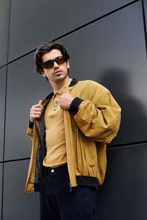 A young man showcases his trendy autumn attire while striking a confident pose outdoors in a chic setting.の写真素材