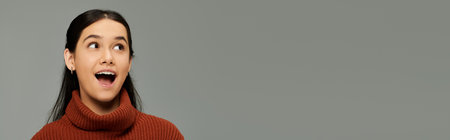 A young woman in a cozy sweater showcases her excitement, radiating positive emotions effortlessly.の写真素材