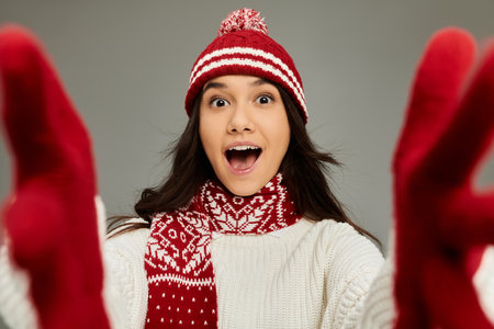 A young woman in a cozy red and white outfit joyfully displays her playful winter spirit.の写真素材