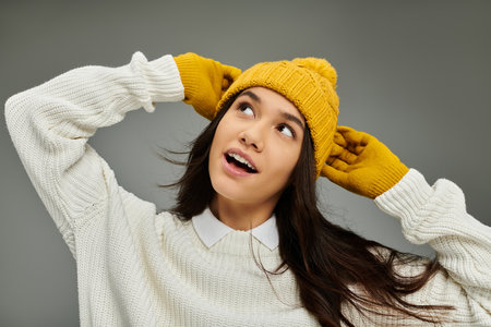 The stylish young woman radiates joy while adorning a warm hat and sweater.