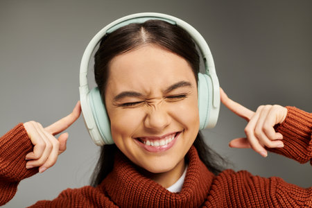 A young woman joyfully listens to music, wearing headphones and showcasing her stylish outfit.の写真素材